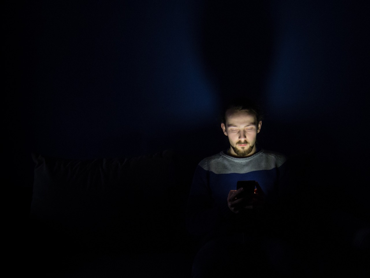 man silhoutted by computer screen at night