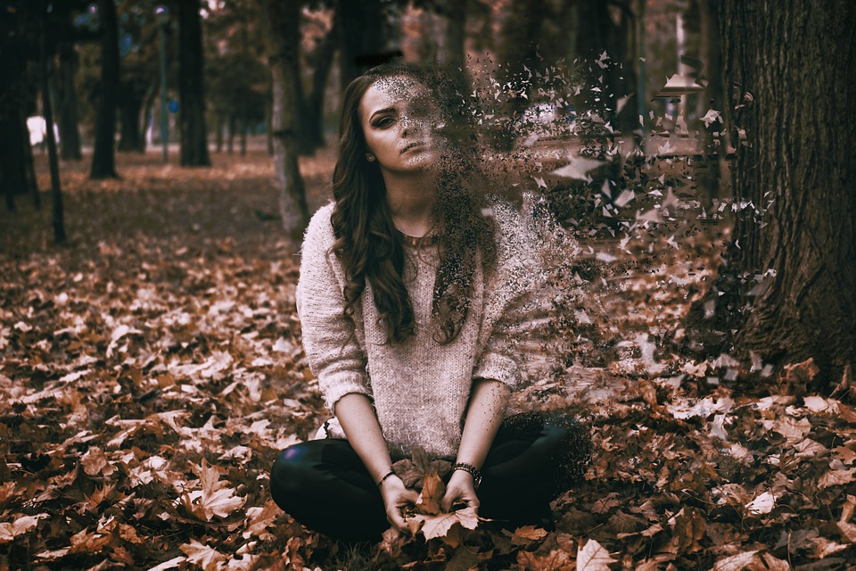 sad woman sitting among fallen leaves
